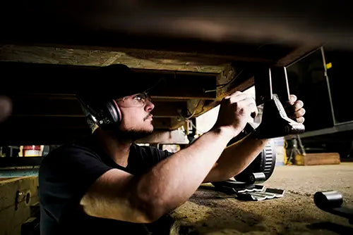 Mécanicien effectuant une inspection complète sous une remorque dans notre garage spécialisé.